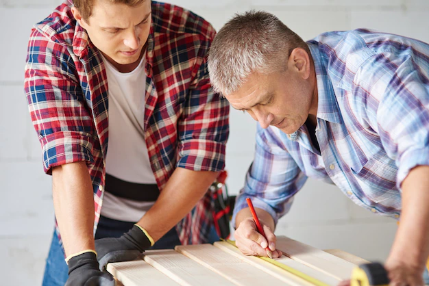 close-up-experienced-carpenter-his-younger-employee_329181-15622